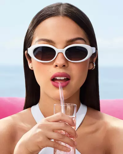 Olivia Rodrigo con lentes de sol blancos y un look de labios malva.