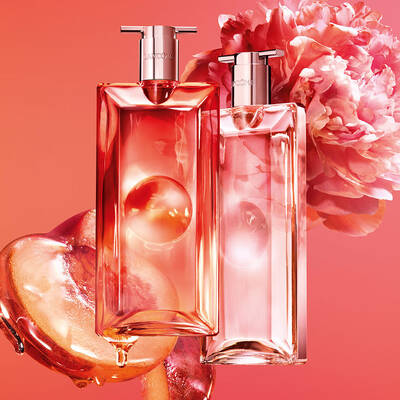Dos frascos de perfume Lancome con duraznos y una flor rosa.